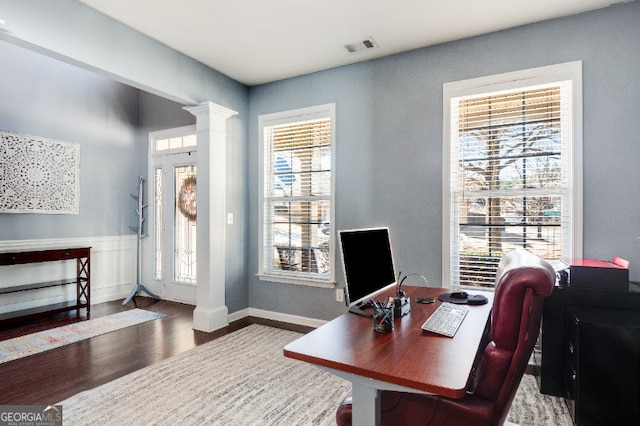 office area with visible vents, dark wood-type flooring, plenty of natural light, and decorative columns