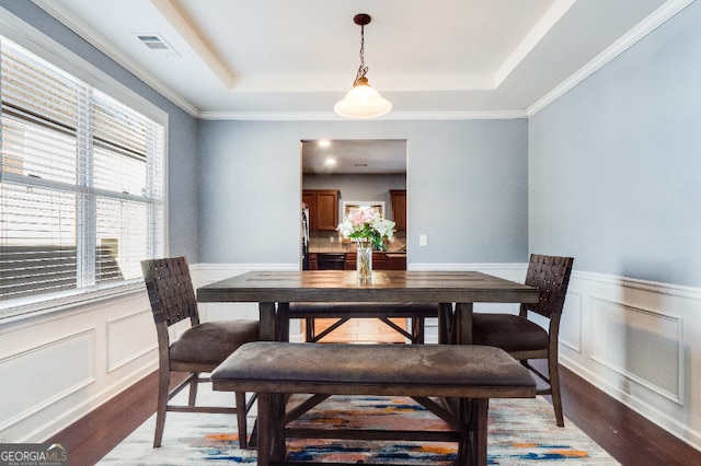 dining space featuring a wainscoted wall, a tray ceiling, light wood-style flooring, and visible vents