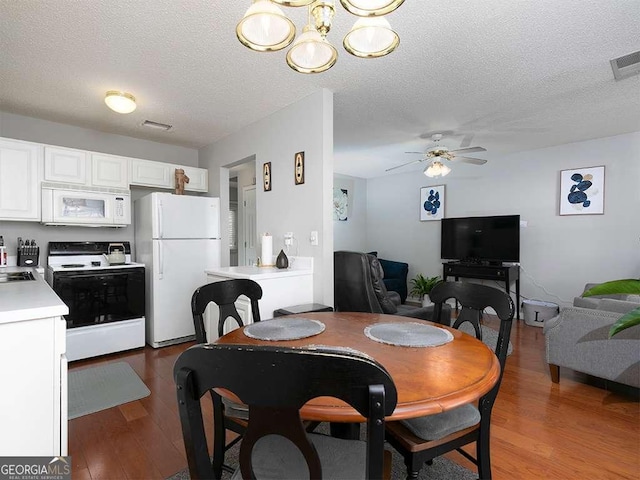 dining area featuring ceiling fan, a textured ceiling, wood finished floors, and visible vents