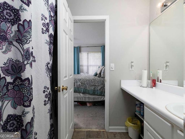 ensuite bathroom with connected bathroom, vanity, and baseboards