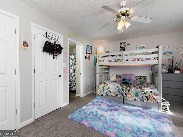 bedroom featuring baseboards, dark carpet, ceiling fan, and a textured ceiling