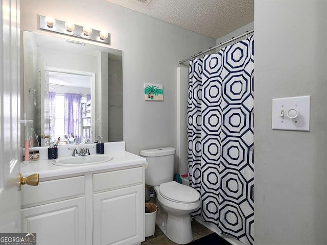bathroom featuring a textured ceiling, toilet, a shower with shower curtain, and vanity
