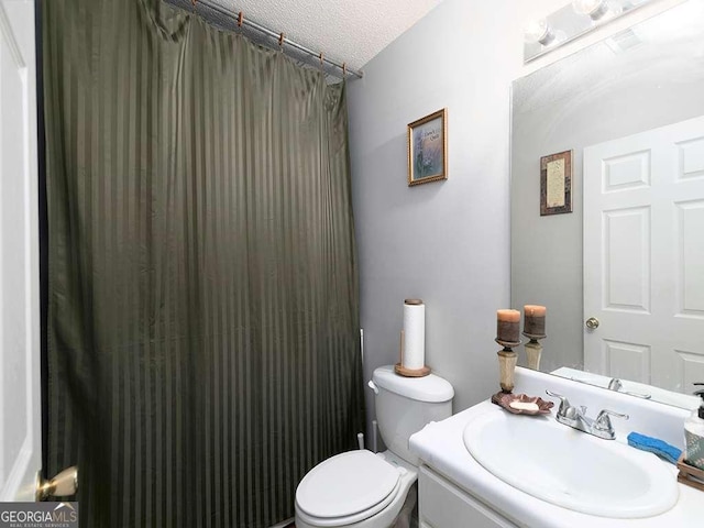 bathroom with toilet, a textured ceiling, and vanity