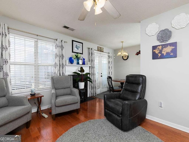 living area featuring a textured ceiling, ceiling fan, dark wood-style flooring, visible vents, and baseboards