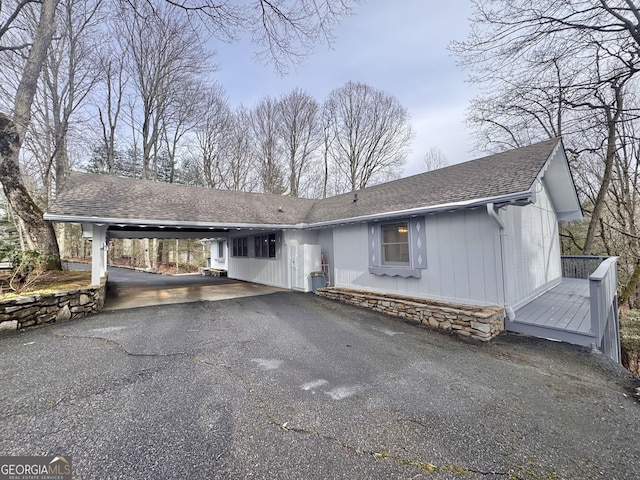 view of front of home with an attached carport, aphalt driveway, stone siding, and roof with shingles