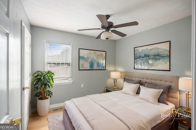 bedroom with ceiling fan, light wood finished floors, visible vents, and baseboards