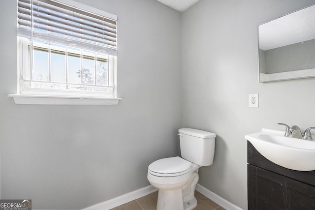 bathroom featuring toilet, tile patterned flooring, vanity, and baseboards