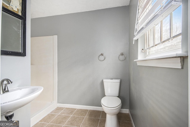 half bath featuring a sink, toilet, baseboards, and tile patterned floors