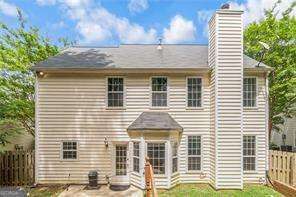 back of property featuring a chimney, fence, and a patio