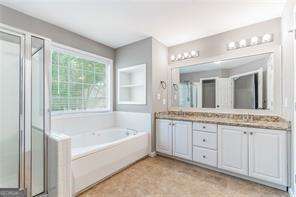 full bathroom with double vanity, a garden tub, and a shower stall