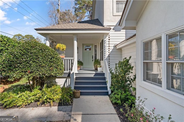 entrance to property featuring a shingled roof and stucco siding