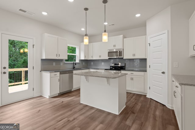 141 Roxeywood Way, Winder, GA 30680 - kitchen with stainless steel appliances, a sink, decorative backsplash, a center island, and white cabinets