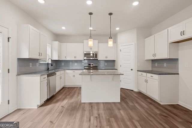 141 Roxeywood Way, Winder, GA 30680 - kitchen featuring stainless steel appliances, a sink, a kitchen island, tasteful backsplash, and light wood finished floors