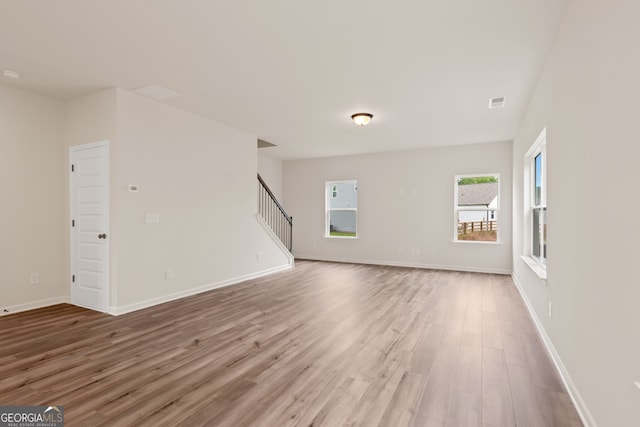 141 Roxeywood Way, Winder, GA 30680 - unfurnished living room with wood finished floors, plenty of natural light, stairs, and baseboards