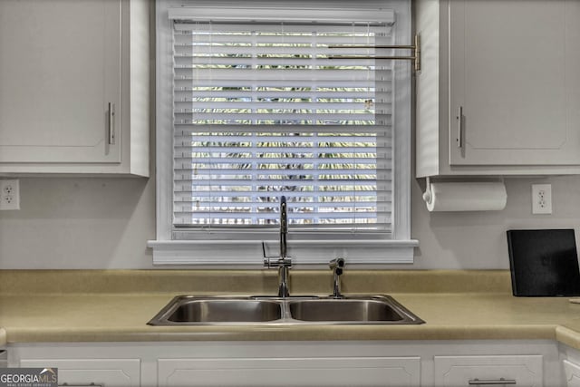 kitchen featuring light countertops, a sink, and white cabinetry