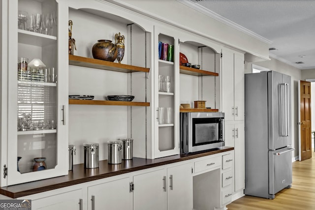 interior space featuring open shelves, dark countertops, ornamental molding, and stainless steel appliances