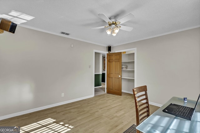 unfurnished office with a textured ceiling, a ceiling fan, baseboards, visible vents, and light wood-style floors