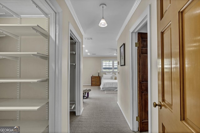 hall with carpet floors, visible vents, crown molding, and baseboards