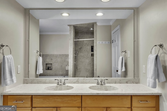 full bathroom featuring a tile shower, double vanity, a sink, and crown molding