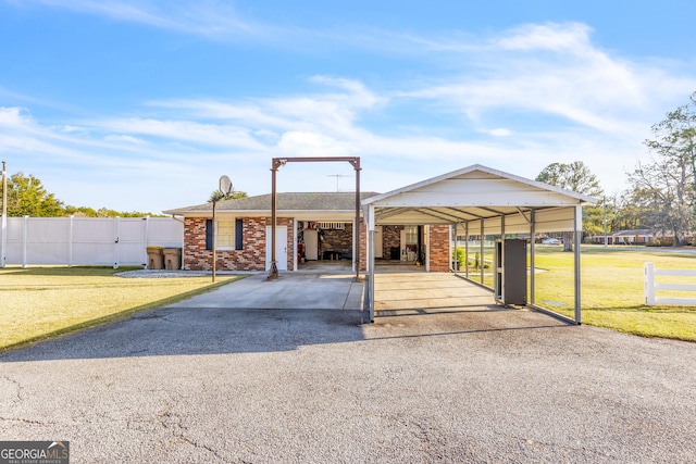 view of front of property with aphalt driveway, brick siding, fence, a carport, and a front lawn