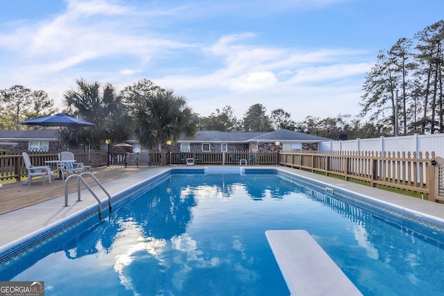 view of pool with a wooden deck, a diving board, fence, and a fenced in pool