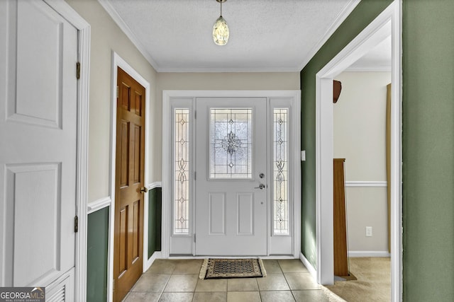 foyer with a textured ceiling, light tile patterned floors, baseboards, and crown molding