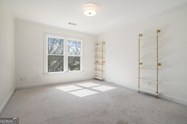 empty room featuring carpet floors, visible vents, crown molding, and baseboards