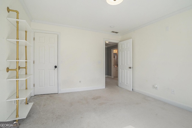 carpeted spare room with baseboards, visible vents, and crown molding