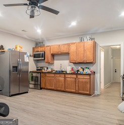 kitchen with dark countertops, light wood finished floors, stainless steel appliances, and brown cabinetry
