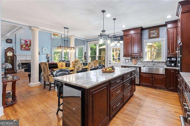 kitchen featuring a center island, decorative light fixtures, open floor plan, a sink, and a kitchen breakfast bar