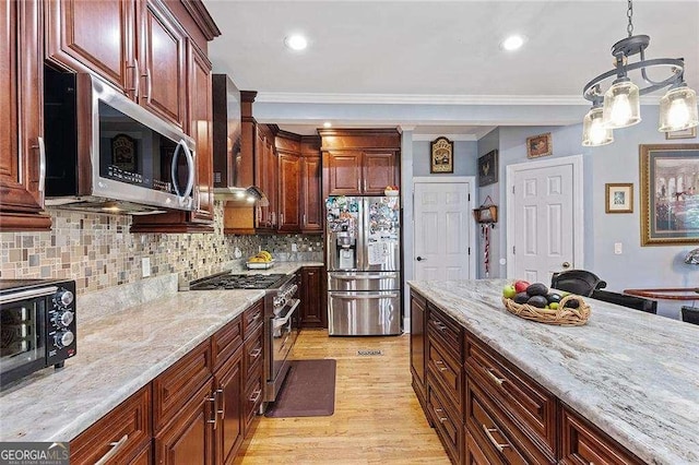 kitchen with light stone countertops, appliances with stainless steel finishes, extractor fan, and decorative light fixtures