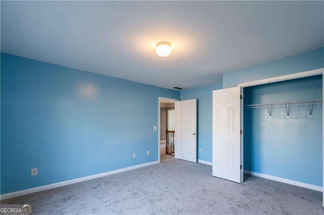 unfurnished bedroom with carpet floors, a closet, visible vents, and baseboards