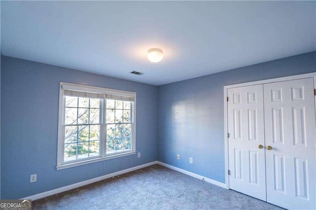 unfurnished bedroom featuring carpet floors, a closet, visible vents, and baseboards