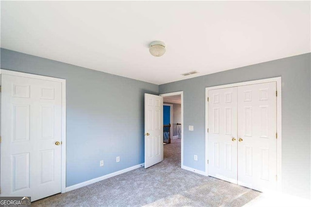 unfurnished bedroom featuring light carpet, baseboards, visible vents, and a closet