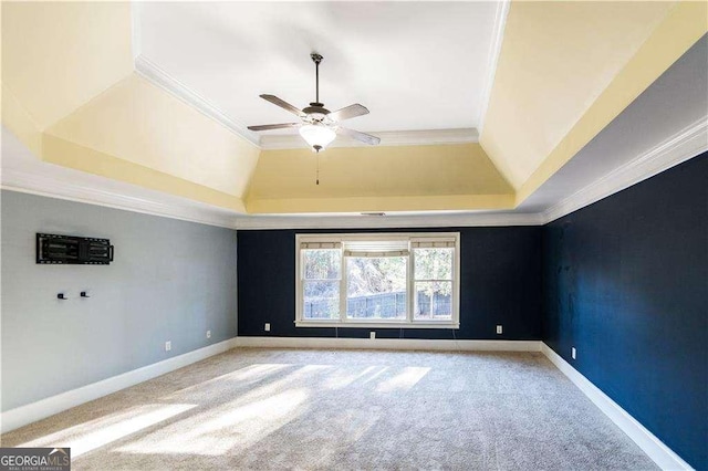 spare room with light carpet, a ceiling fan, baseboards, a tray ceiling, and crown molding