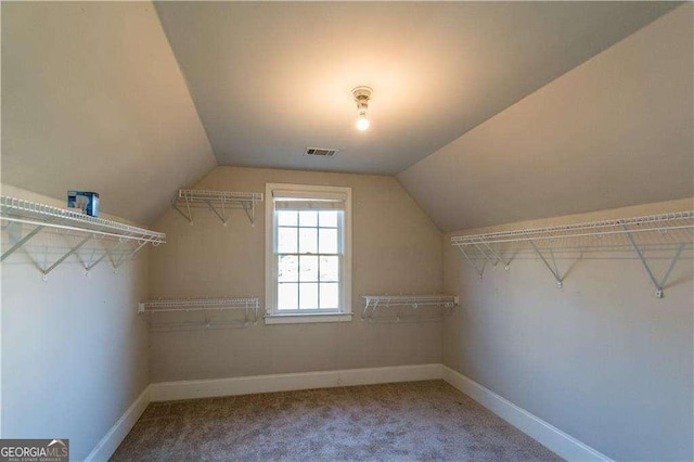 walk in closet with carpet, visible vents, and vaulted ceiling