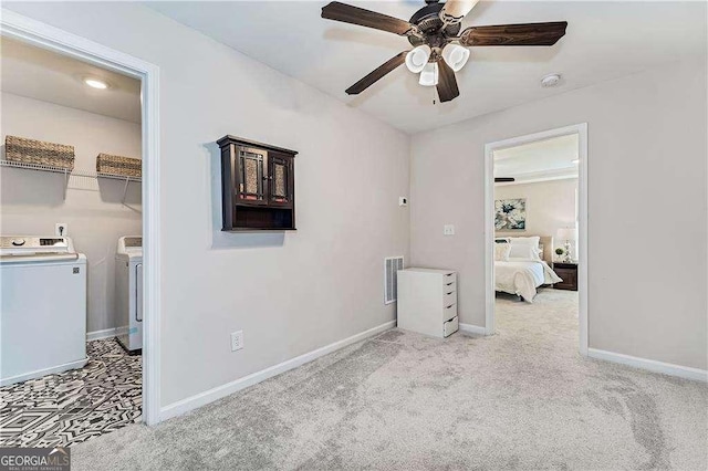 bedroom with light colored carpet, visible vents, baseboards, washer and dryer, and a walk in closet