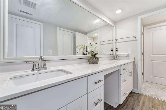 full bathroom with wood finished floors, visible vents, a sink, and double vanity