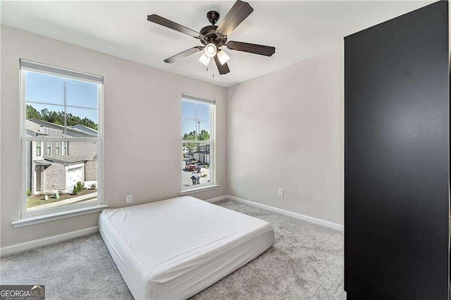 bedroom with light carpet, ceiling fan, and baseboards