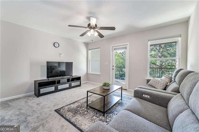 living area with a ceiling fan, light carpet, and baseboards