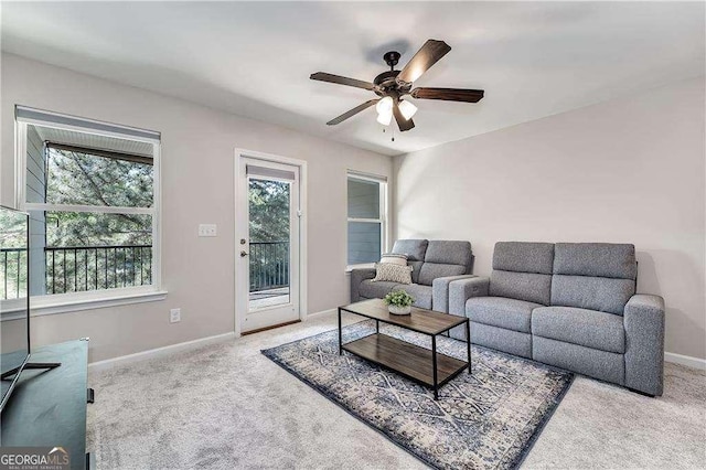 living area with baseboards, ceiling fan, and light colored carpet