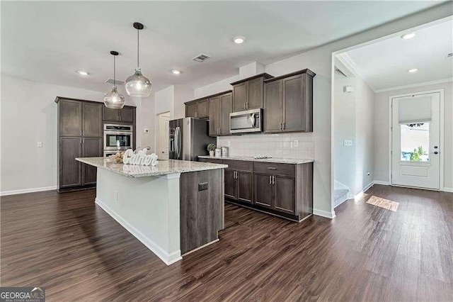 kitchen featuring a center island, visible vents, appliances with stainless steel finishes, light stone countertops, and decorative light fixtures