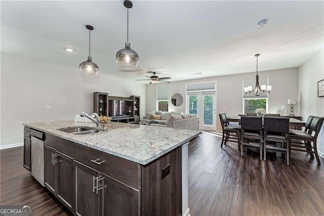 kitchen featuring dark wood finished floors, stainless steel dishwasher, a sink, and a center island with sink