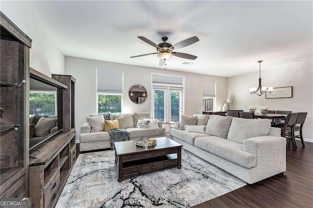 living room with dark wood-style floors, visible vents, and ceiling fan with notable chandelier