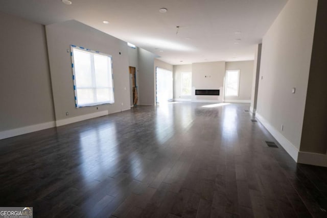 unfurnished living room featuring dark wood-style flooring, visible vents, a fireplace, and baseboards