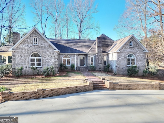 view of front of house featuring a front yard, brick siding, and a chimney