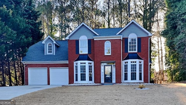 colonial home with a garage, concrete driveway, and brick siding