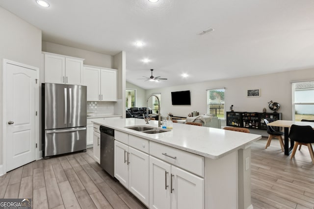 kitchen featuring stainless steel appliances, open floor plan, white cabinetry, and a sink