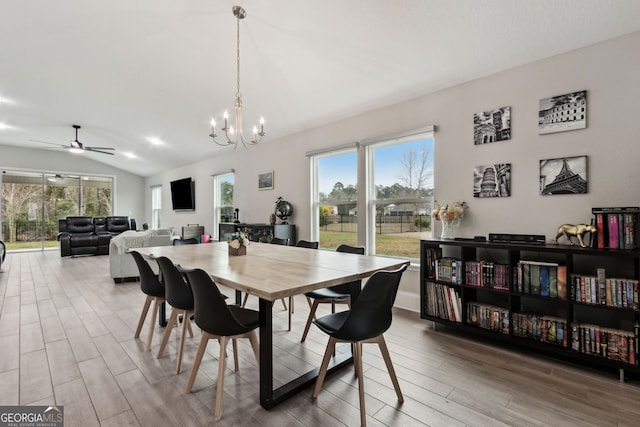 dining room featuring ceiling fan with notable chandelier, a healthy amount of sunlight, vaulted ceiling, and wood finished floors