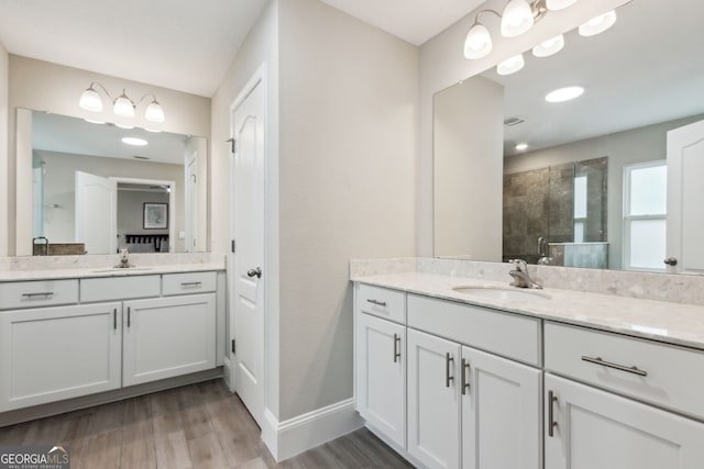 full bath with two vanities, a sink, a shower stall, and wood finished floors